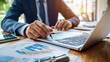 © ADD PHOTO - Businessman analyzing financial data on laptop in office setting