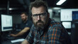 © Number One Studio - focused man with glasses and beard working in office environment, showing determination and concentration. background features computer screens