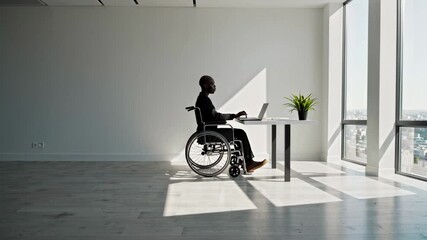 Poster - Sunlight illuminates manager in wheelchair working on laptop at desk in modern office, demonstrating inclusivity and accessibility in workplace