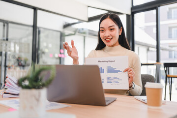 Wall Mural - Asian businesswoman presenting marketing report during online meeting in modern office.