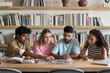 © fizkes - Group of four students gathered around table in library, engaged in collaborative study session, working together on project, researching topic, or preparing for academic assignment. Higher education
