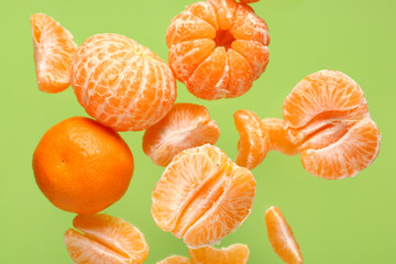 Wall Mural - Flying sweet peeled mandarins on green background