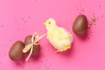 Wall Mural - Sweet chocolate Easter eggs with bow and chick on pink background