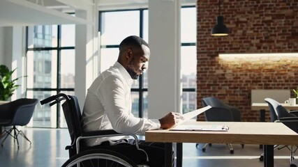 Aufkleber - Young african american businessman in wheelchair reading documents at desk in modern office, demonstrating inclusivity and accessibility in workplace