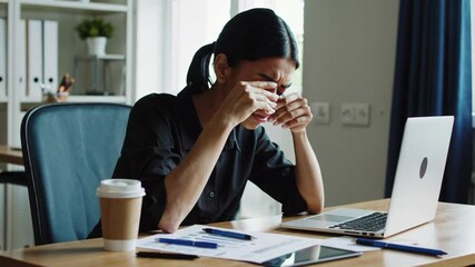 Poster - Professional businesswoman experiencing work related stress, rubbing temples while suffering from painful headache during intense moment at modern office workspace, revealing workplace exhaustion