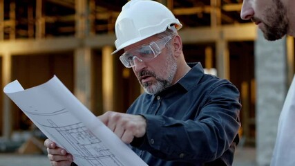 Poster - Senior engineer wearing safety glasses and hardhat shows blueprints to a young architect on a construction site, captured in a slow motion multi frame sequence