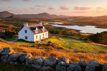 Wall Mural - White cottage overlooking scenic Scottish highlands at sunset