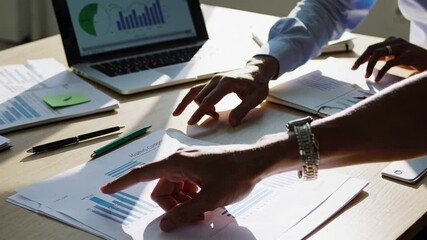 Poster - Business colleagues analyze financial charts and graphs, discussing data and pointing at key figures on documents and laptop screen in a brightly lit office environment