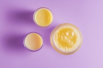 Wall Mural - Three glasses filled with orange juice on a purple surface