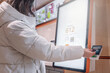 © Vladimir Razgulyaev - A woman dressed in a stylish white coat is making a convenient mobile payment at a modern selfservice kiosk A white woman in a jacket pays for an order with a bank card in a restaurant through a