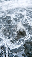Poster - Close up view of white water foam and dark gray rocks, with a textured surface and dynamic motion. The image has a cool color palette and shows water