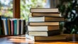 © los3amigos - Un grupo de libros apilados sobre una mesa, iluminados por la luz natural que entra por una ventana.