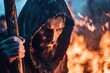 © Sergio Lucci - A hooded man with a staff stands in the firelight, lost in thought, evoking mystery and inner conflict