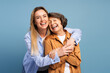 © Maria Vitkovska - Happy mother and daughter embracing and smiling on blue background