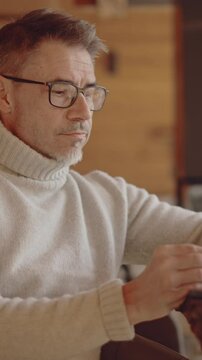 Fototapete -  - Mature male professional managing business remotely from cozy warm workspace of wooden weekend cottage. Businessman using digital technology in home office. Entrepreneur working on winter vacation.
