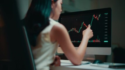 Poster - Professional businesswoman reviewing stock market data on computer screen, working late with focused expression in shadowy corporate workspace