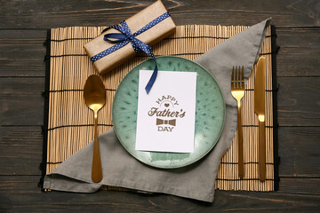 Wall Mural - Beautiful table setting with greeting card and gift box on black wooden background. Father day celebration concept