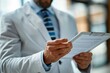 © dyshlivenko - A medical professional in a white coat examines patient notes on a clipboard in a well-lit office, demonstrating attention to detail and care for patient health