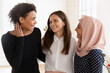 © fizkes - Multicultural women colleagues, students, friends hugging standing together indoor, enjoy effective teamwork, result and reached goals, having warm relationships at work. Friendship, equality, loyalty