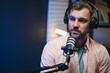 © Serhii - Man smiling while recording podcast in studio
