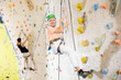 © JackF - senior female climber in helmet and with safety rope hangs near climbing wall in gym. dynamic sports