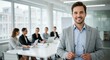 © Firman Dasmir - Smiling businessman in bright office with team meeting in background
