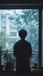 © Ben Kuang - A contemplative young Asian man gazes out at a rainy cityscape from a window.