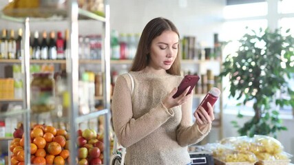 Wall Mural - Young woman buyer scanning qr code for red smoothie in bottle in grocery store