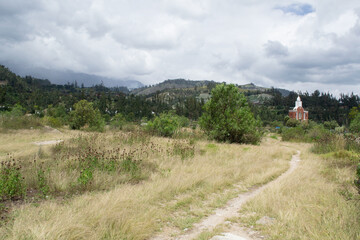 Camino a la montaña en medio de la naturaleza rumbo a una capilla de campo santo en Yungay Perú en medio de un cielo gris