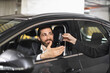© sofiko14 - Smiling Caucasian businessman receives car keys from another person inside parking garage. Concept of car rental, business travel, mobility solution.
