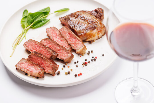Fototapete -  - A perfectly cooked sliced striploin steak with a juicy, tender texture, served alongside a glass of rich red wine