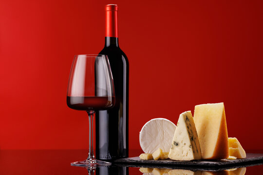Fototapete -  - A refined selection of aged cheeses presented on a board, accompanied by a glass of wine
