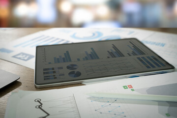 Poster - a tablet displaying graphs analyzing sales data and growth graph and charts alongside printed report