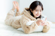 © wheeljack - 部屋でスマホを操作する若い女性