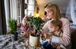 © NDABCREATIVITY - Happy single parent, woman with a little son is planting houseplants at home. Home gardening