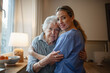 © Halfpoint - Caring healthcare worker visiting a senior patient at home, hugging her.