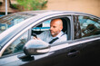 © Westend61 - Businessman driving vehicle and using smartphone