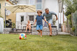 © Westend61 - Father and son playing football in garden
