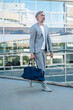 © Westend61 - Fashionable mature businessman with travelling bag on the go