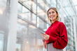© Westend61 - Businesswoman in red blouse holding a tablet in a modern office