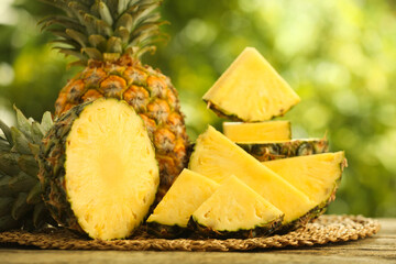 Wall Mural - Fresh ripe pineapples on wooden table against blurred background, closeup