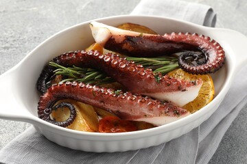 Sticker - Fried octopus with vegetables, lemon and rosemary in baking dish on grey textured table, closeup