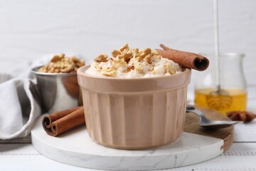 Wall Mural - Tasty rice pudding with cinnamon served on white wooden table, closeup