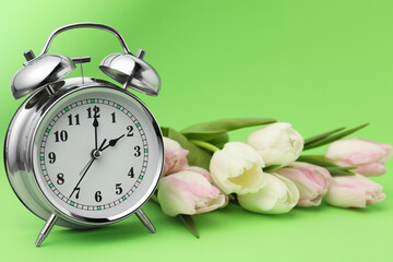 Poster - Spring time. Alarm clock and beautiful tulips on green background, closeup