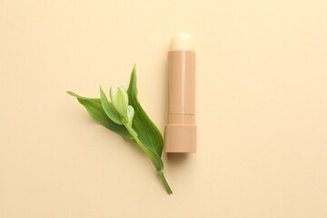 Sticker - Lip balm and flower with leaves on beige background, top view