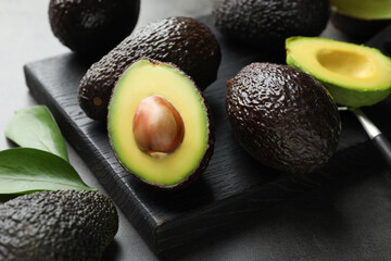 Wall Mural - Fresh ripe avocados, spoon and leaves on grey table, closeup