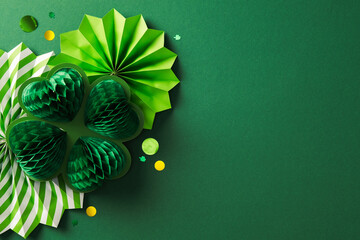 Wall Mural - Happy St. Patrick's Day concept. Flat lay composition with honeycomb paper four leaf clover and decorative paper fans on dark green table. St. Patrick's Day background