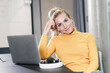 © Westend61 - Portrait of casual businesswoman sitting at table in office with laptop