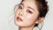 © Platon - Youthful Asian model with fresh, dewy makeup and soft, wavy hairstyle, looking gently to the side on a light, neutral background. Suitable for beauty product advertising and cosmetic campaigns