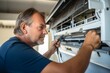 © Mountains Hunter - A middle-aged air conditioning technician performs repairs at a site. Generative AI.